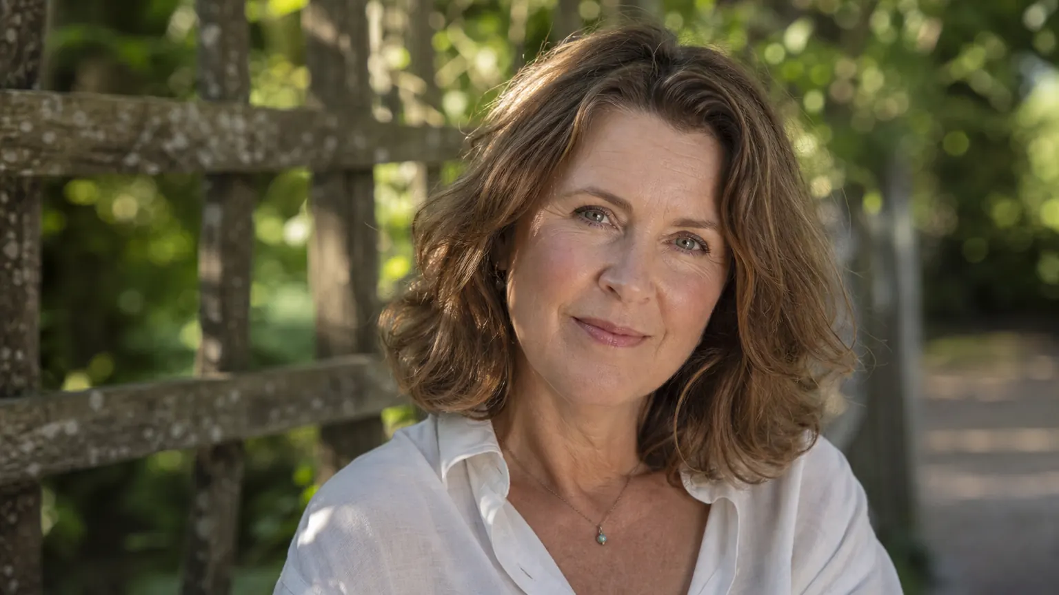 Woman with glowing hydrated skin smiling outdoors, photographed in soft natural afternoon light